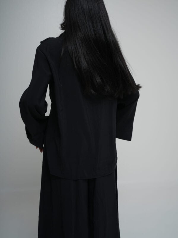 Black longline shirt worn over matching wide-leg trousers in lightweight summer fabric