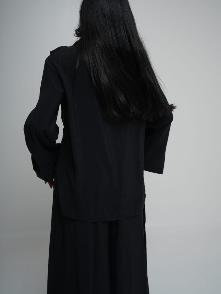 Black longline shirt worn over matching wide-leg trousers in lightweight summer fabric