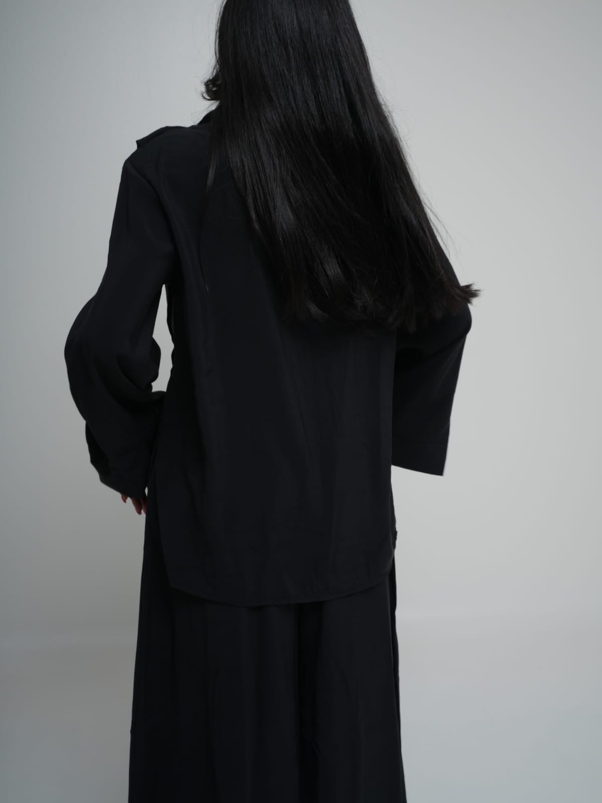 Black longline shirt worn over matching wide-leg trousers in lightweight summer fabric