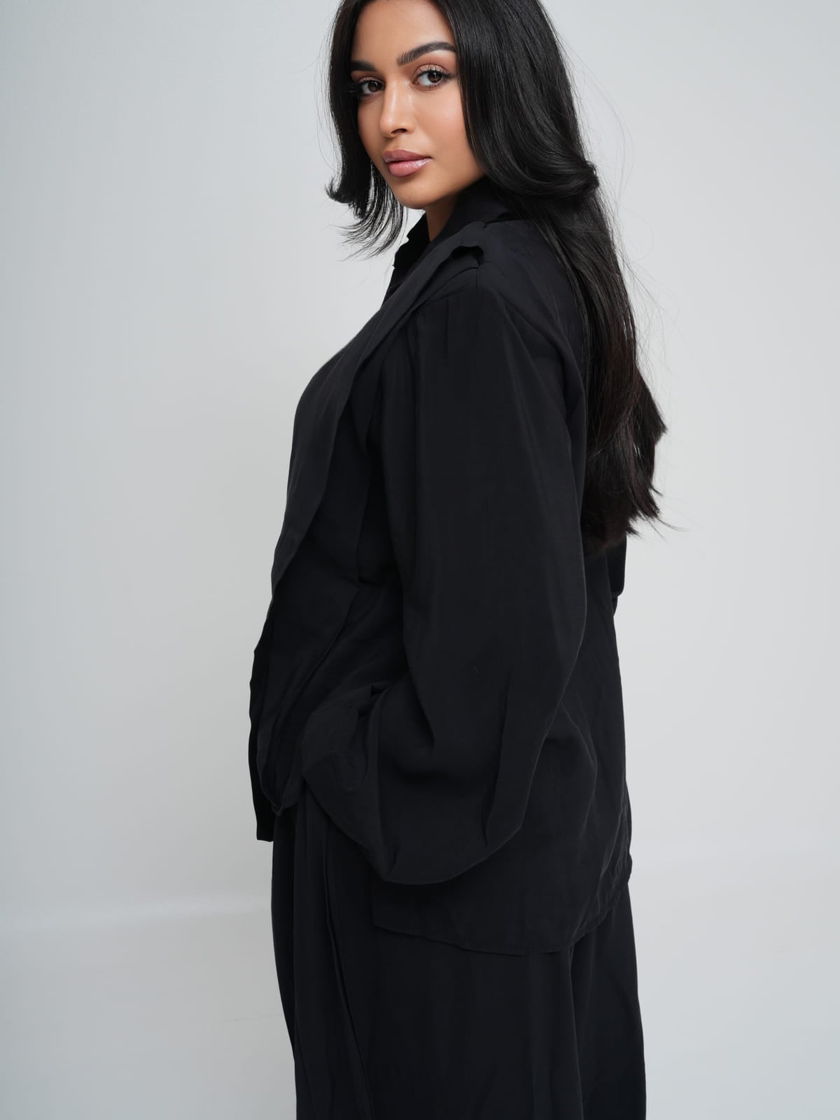 Black longline shirt worn over matching wide-leg trousers in lightweight summer fabric